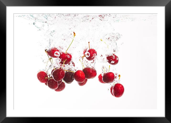 Red cherries splashing into crystal clear water with air bubbles. Isolated on a white background. Framed Mounted Print by Przemek Iciak