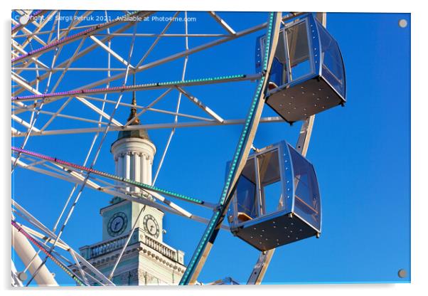 Empty cabins of the city's ferris wheel against the background of the blue sky and the spire of the old tower. Acrylic by Sergii Petruk