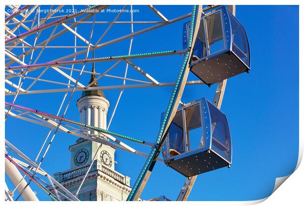Empty cabins of the city's ferris wheel against the background of the blue sky and the spire of the old tower. Print by Sergii Petruk