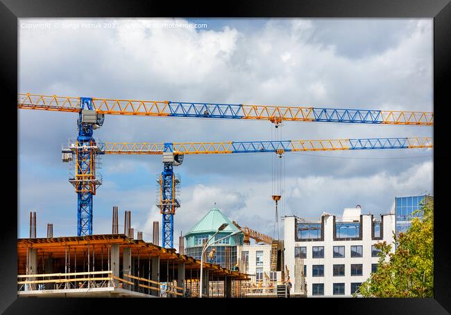 Construction site with tower cranes and the construction of a residential building against the backdrop of a cloudy sky. Framed Print by Sergii Petruk