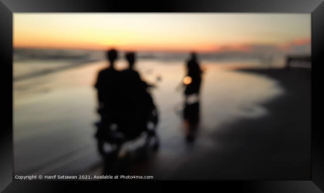 Young people motorcycling on a wet sand beach Framed Print by Hanif Setiawan