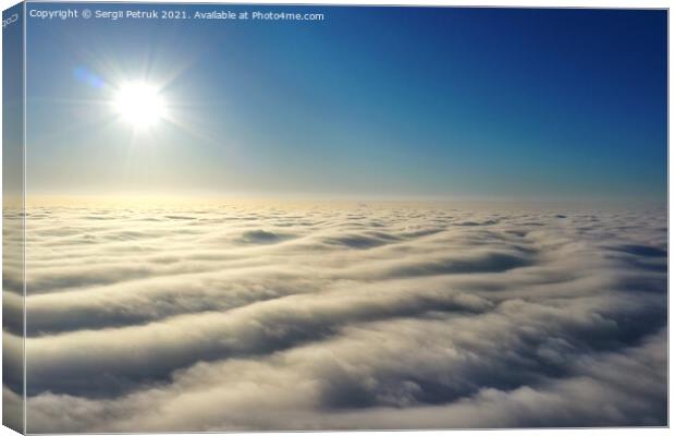 Aerial view, bright sun above the horizon and over dense wavy gray clouds against a deep blue sky. Canvas Print by Sergii Petruk