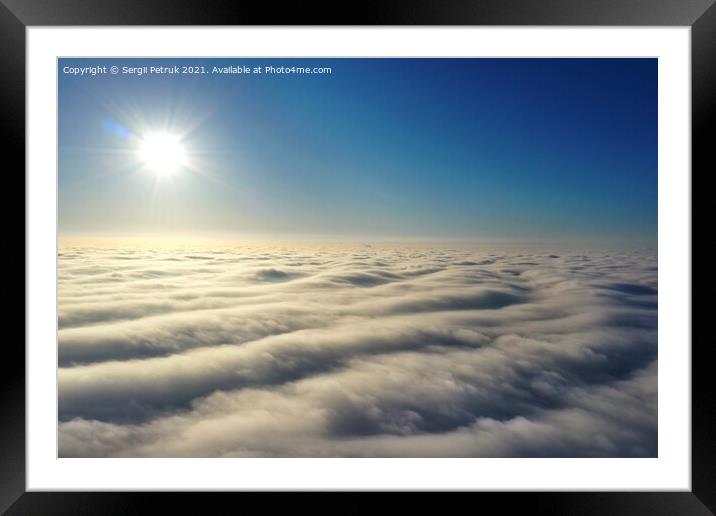 Aerial view, bright sun above the horizon and over dense wavy gray clouds against a deep blue sky. Framed Mounted Print by Sergii Petruk