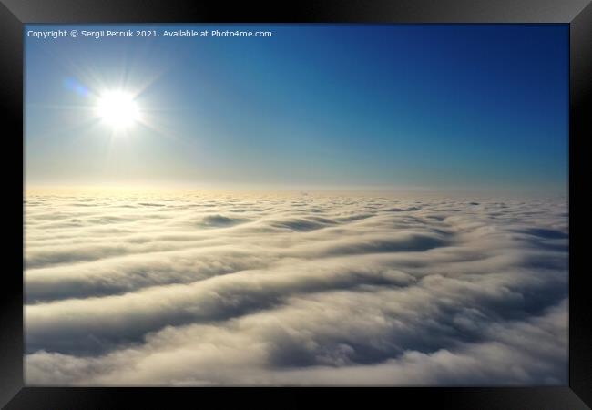Aerial view, bright sun above the horizon and over dense wavy gray clouds against a deep blue sky. Framed Print by Sergii Petruk