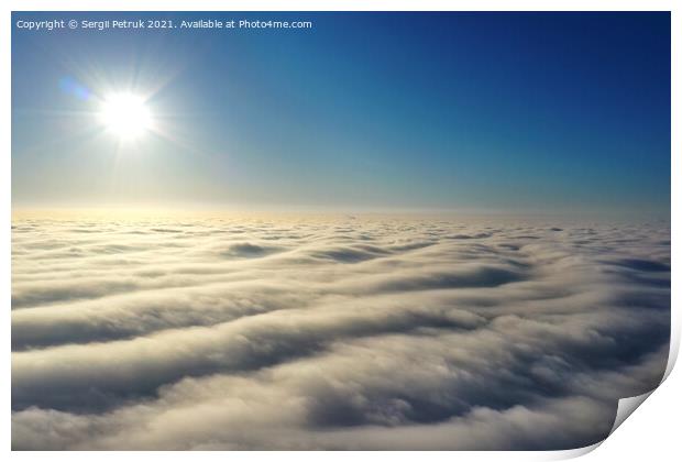 Aerial view, bright sun above the horizon and over dense wavy gray clouds against a deep blue sky. Print by Sergii Petruk