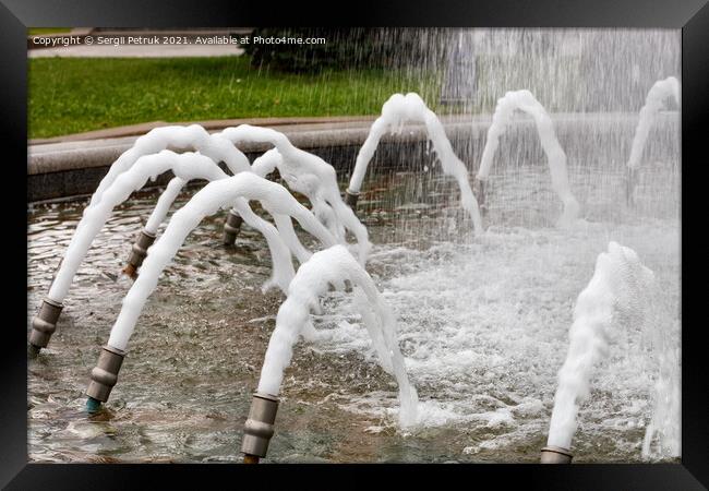 Foamed, dense jets of water burst from metal nozzles in the city fountain. Framed Print by Sergii Petruk
