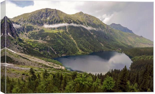 Wide angle top view of Morskie Oko naturally formed lake pond in Tatra Mountains in Poland. High mountain landscape with dramatic clouds covered with snow and trees at national park High Tatras Europe Canvas Print by Arpan Bhatia