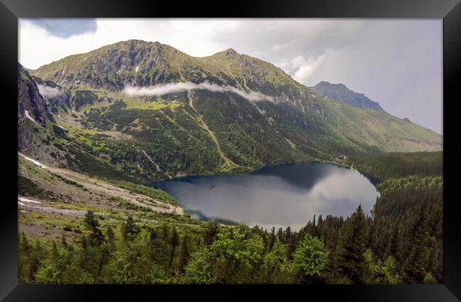 Wide angle top view of Morskie Oko naturally formed lake pond in Tatra Mountains in Poland. High mountain landscape with dramatic clouds covered with snow and trees at national park High Tatras Europe Framed Print by Arpan Bhatia