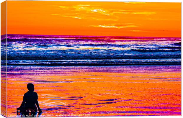 A young boy enjoys the sunset at a sand beach. Canvas Print by Hanif Setiawan