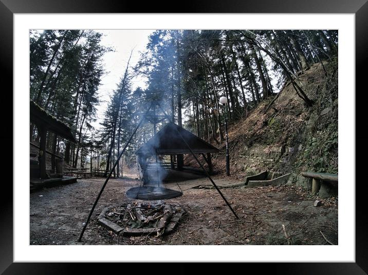 South Poland: Barbecue location in the middle of the forest surrounded with tall trees. Wilderness wide angle view of smoke coming from fire against abandoned shed in the peaceful environment Framed Mounted Print by Arpan Bhatia