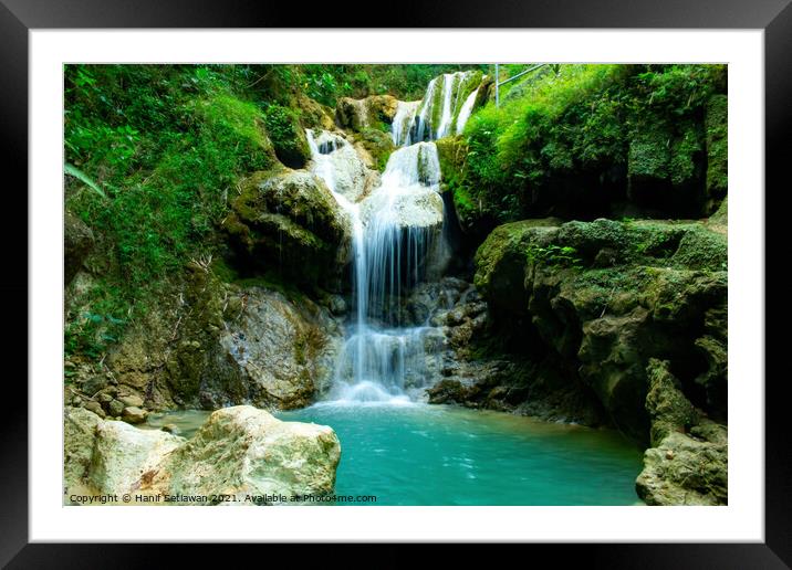 A waterfall flowing over rocks into a river. Framed Mounted Print by Hanif Setiawan