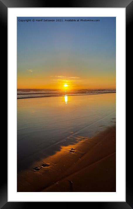 Wide sand beach reflecting orange sunset sunlight. Framed Mounted Print by Hanif Setiawan
