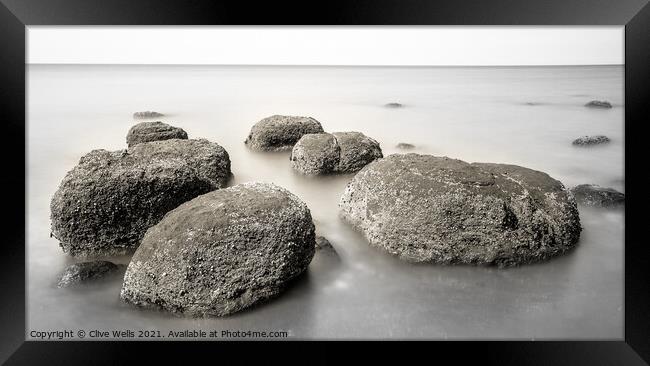 Boulders on smooth sea Framed Print by Clive Wells