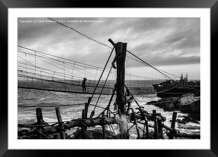 A man on a swinging rope foot bridge. Framed Mounted Print by Hanif Setiawan