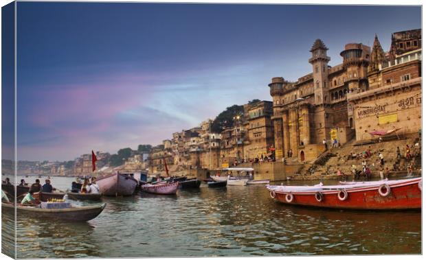 Varanasi, India : People and tourists on wooden boat sightseeing in Ganges river near Munshi ghat against ancient city architecture as viewed from a boat during morning time Canvas Print by Arpan Bhatia