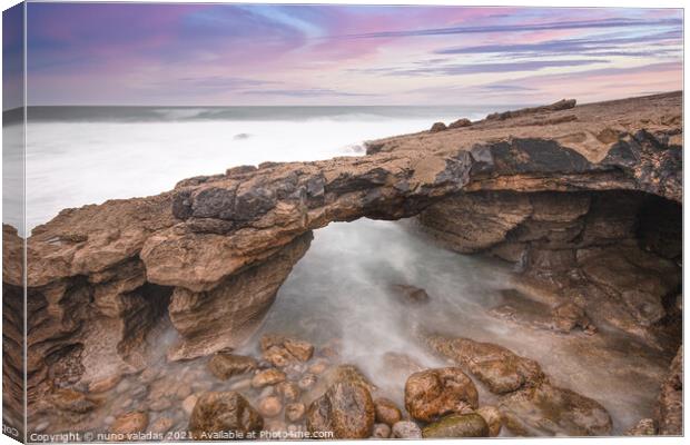 Arch shaped rock formation in the coastline at the sunset Canvas Print by nuno valadas