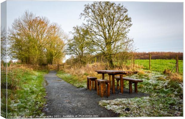 Wooden table and chairs at a seating area on a countryside trail in winter Canvas Print by SnapT Photography