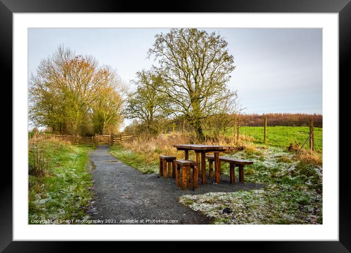 Wooden table and chairs at a seating area on a countryside trail in winter Framed Mounted Print by SnapT Photography