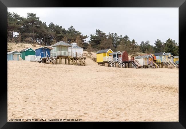 Coloured beach huts on the sand dunes Framed Print by Clive Wells
