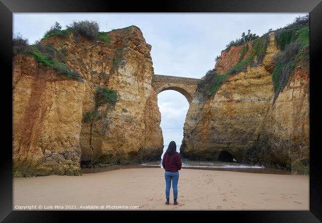 Woman traveler at Praia dos estudantes beach with arch bridge in Lagos, Portugal Framed Print by Luis Pina