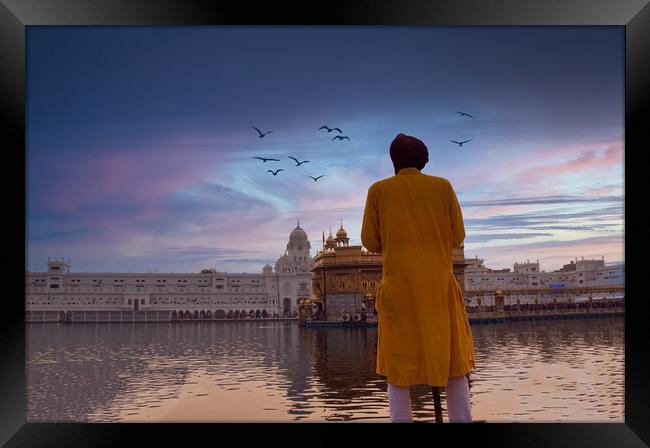 Amritsar, India: Unidentified Sikh Guard with spear standing and looking around near Sri Harmandir Sahib or Golden Temple pond against dramatic sunrise and birds in the sky Framed Print by Arpan Bhatia