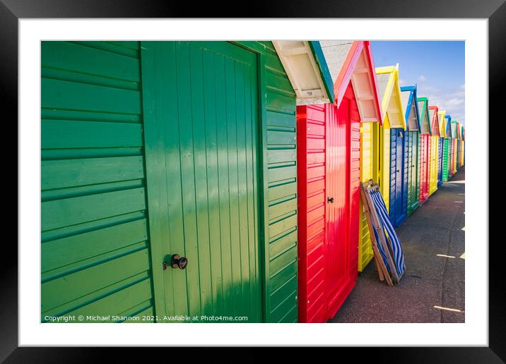 Colourful Beach Huts and a deck chair in Whitby Framed Mounted Print by Michael Shannon