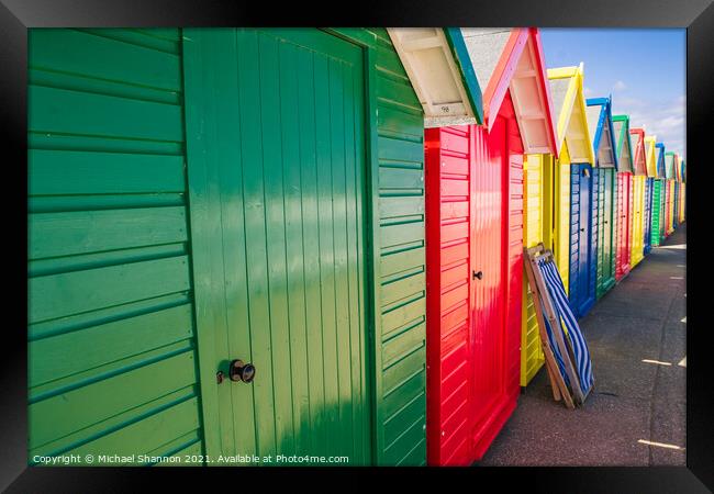Colourful Beach Huts and a deck chair in Whitby Framed Print by Michael Shannon