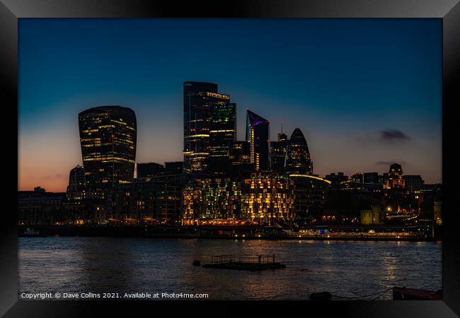 City of London Financial District buildings illuminated at dusk from the south bank walkway by Tower Bridge in London, UK Framed Print by Dave Collins