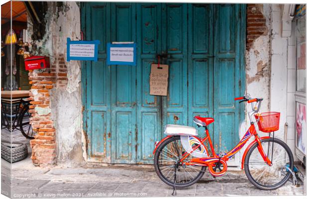 Red bicycle parked by blue doors Canvas Print by Kevin Hellon
