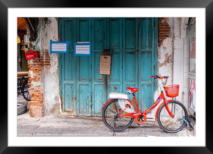 Red bicycle parked by blue doors Framed Mounted Print by Kevin Hellon
