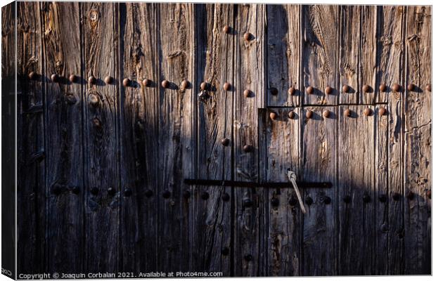 Old and decrepit wooden gate, half lit by the sun, in an unpopul Canvas Print by Joaquin Corbalan