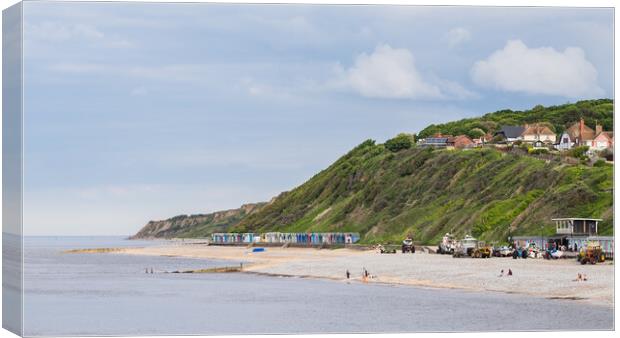 Beach huts sandwiched between the sea and cliffs at Cromer Canvas Print by Jason Wells