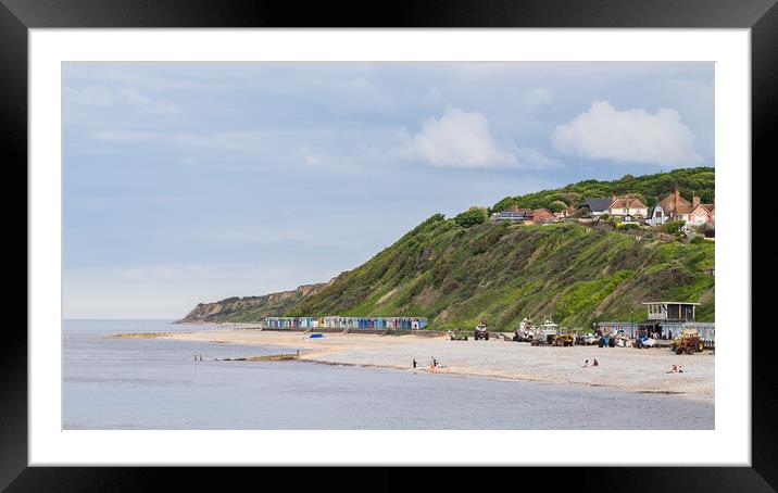 Beach huts sandwiched between the sea and cliffs at Cromer Framed Mounted Print by Jason Wells
