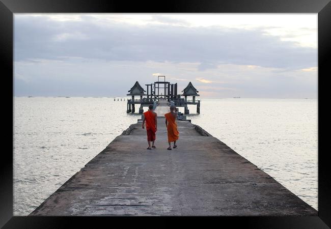 Thai monks on the bridge or Pier , which leads to the never finished and abandoned Thai temple right on the Gulf in Thailand in the province of Chonburi Framed Print by Wilfried Strang