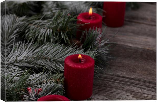 Red glowing candles with fir and wood dark background  Canvas Print by Thomas Baker
