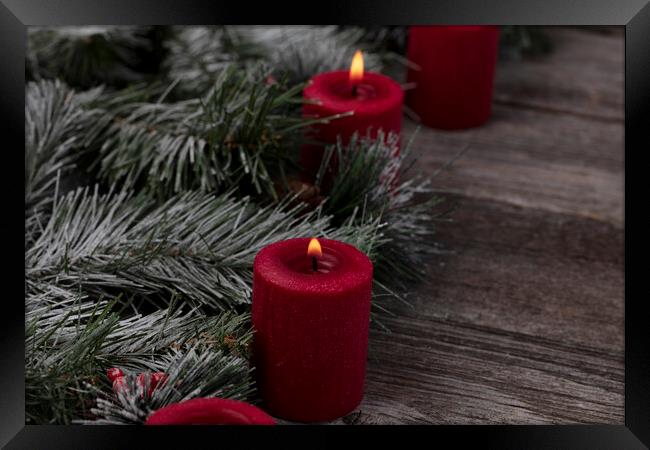 Red glowing candles with fir and wood dark background  Framed Print by Thomas Baker