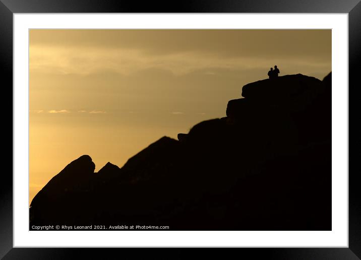 A couple stand silhouetted against a sunset atop stanage edge Framed Mounted Print by Rhys Leonard