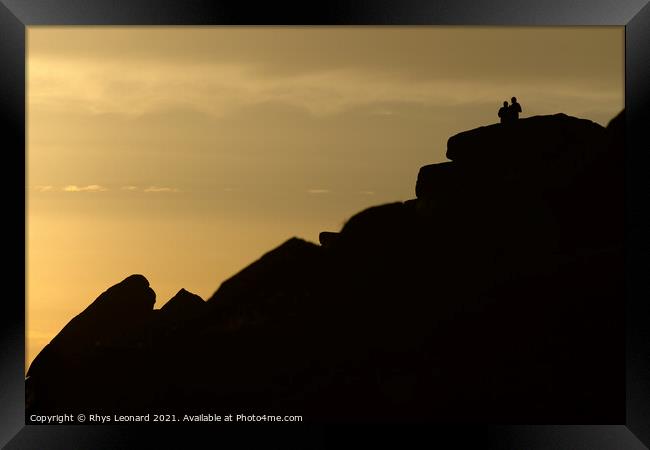 A couple stand silhouetted against a sunset atop stanage edge Framed Print by Rhys Leonard