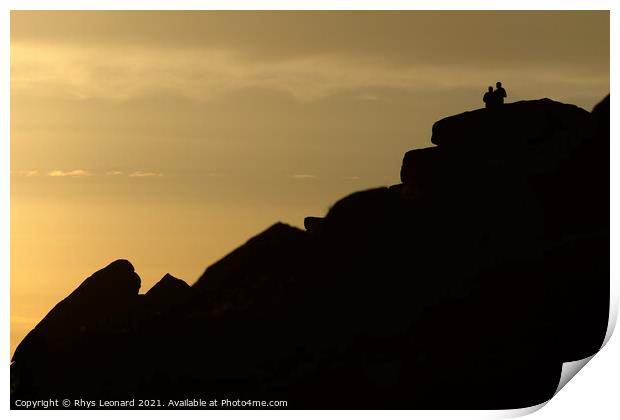 A couple stand silhouetted against a sunset atop stanage edge Print by Rhys Leonard