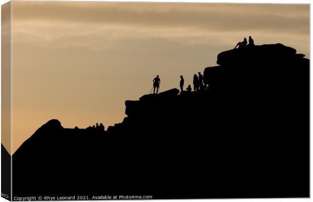 Silhouette of lots of people watching a climber at the summit of stanage edge. Climber wears a harness with tools like nuts, ropes and carabiners. Canvas Print by Rhys Leonard