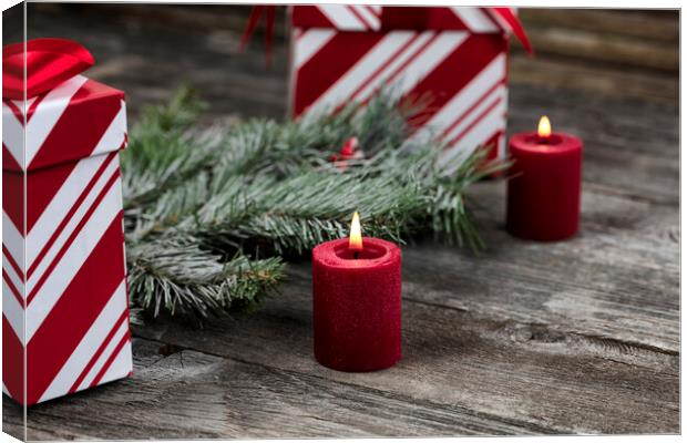 Burning red candle with decorations in background for a merry Ch Canvas Print by Thomas Baker
