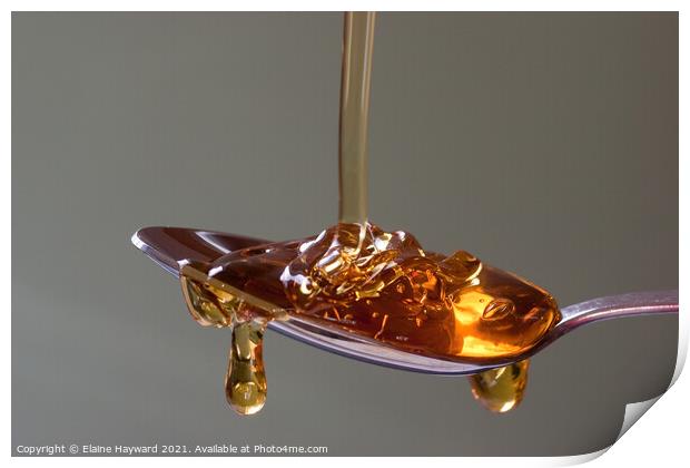 Golden syrup dripping from a silver spoon Print by Elaine Hayward