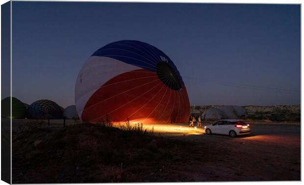 A car parked in front of a hot air balloon with headlights on during night, preparation of a flight in Goreme national park in Cappadocia, Turkey Canvas Print by Arpan Bhatia