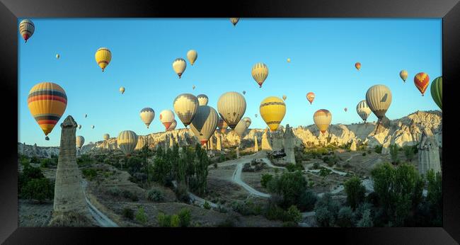 Panorama of bunch of colorful hot air balloon flying early morning in Cappadocia, Turkey against typical rock formation due to volcanic activity in love valley located in Goreme national park Framed Print by Arpan Bhatia