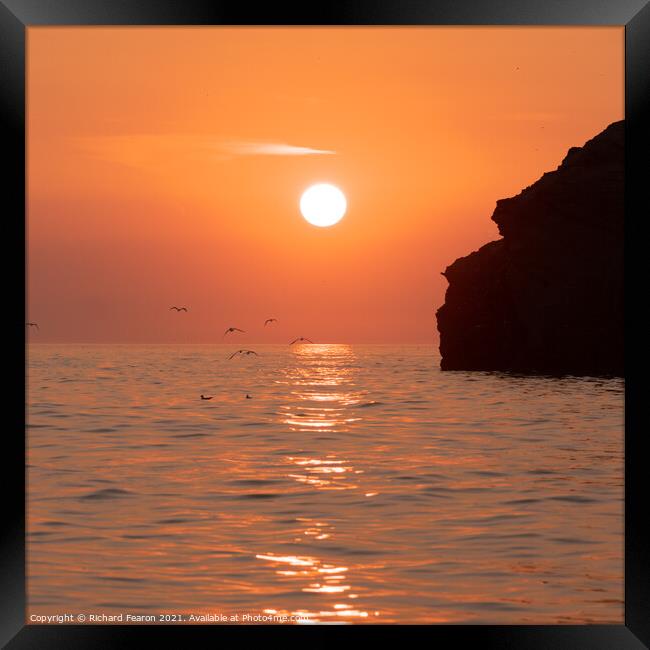 Warm orange sunset reflecting off the sea at South Framed Print by Richard Fearon