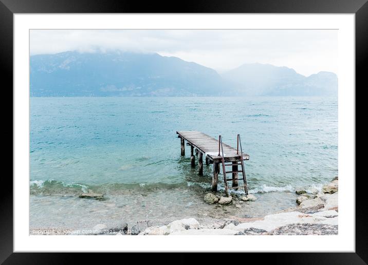 Quiet shore of Lake Garda on a rainy day near the empty jetty. Framed Mounted Print by Joaquin Corbalan