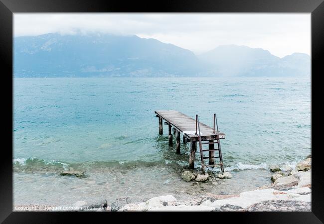 Quiet shore of Lake Garda on a rainy day near the empty jetty. Framed Print by Joaquin Corbalan