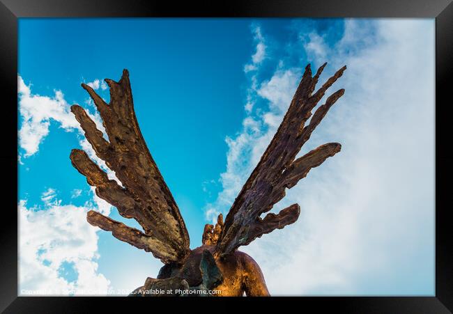 A sculpture of an angel, rear view of its wings against the sky. Framed Print by Joaquin Corbalan
