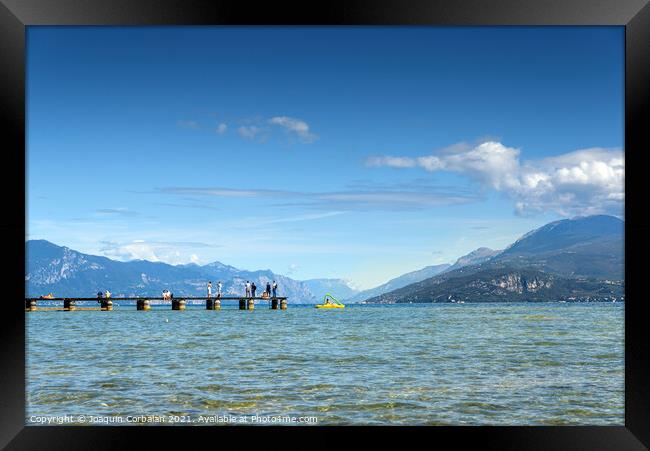 Calm water lake in Garda, Italy with a wooden walkway on a sunny Framed Print by Joaquin Corbalan