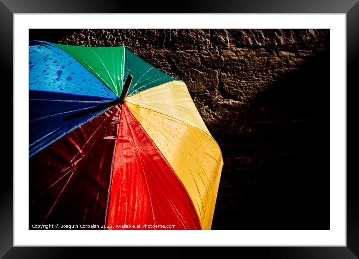 Open umbrella against the intense sun with bright colors and dar Framed Mounted Print by Joaquin Corbalan